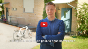 Linkki Virtaa fillariin -kokeilun 2018 minidokumenttiin, jossa kokeiluun osallistunut Mikki Kauste kertoo kokeilun kulusta. Kuvassa Mikki kertoo kokeilusta ulkona, kotitalonsa edessä.