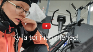 Linkki Virtaa fillariin -talvikokeilun 2020 somevideoon, jossa kokeiluun osallistunut Pipsa-Alisa kertoo fiiliksiä myrskyssä ajetun työmatkan jälkeen. Kuvassa Pipsa-Alisa pyöräkellarissa.